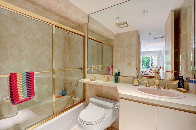 Bathroom featuring combined bath / shower with glass door, tile walls, toilet, vanity, and visible vents | Image 24
