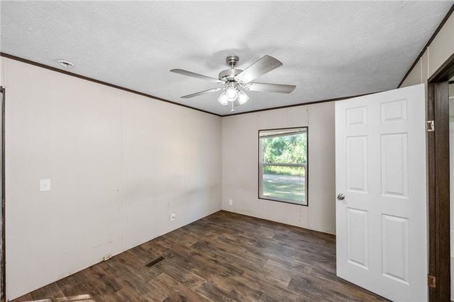 Spare room featuring dark wood finished floors, ceiling fan, a textured ceiling, and ornamental molding | Image 22