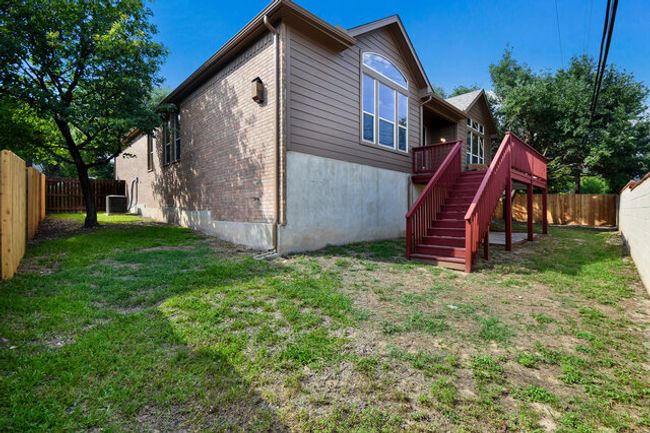 Rear view of house with stairs, a deck, brick siding, and central AC | Image 19