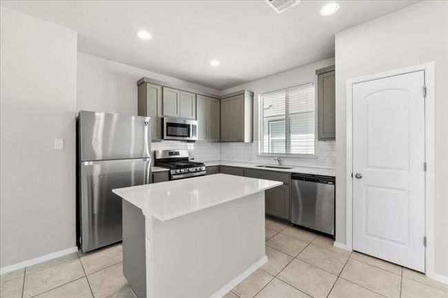 Kitchen featuring gray cabinets, tasteful backsplash, a sink, and stainless steel appliances | Image 12