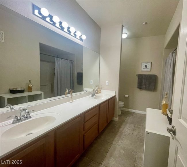 Bathroom with toilet, curtained shower, double vanity, and a sink | Image 35