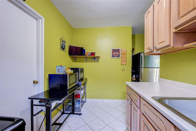 Kitchen with stainless steel appliances, light tile patterned floors, and light countertops | Image 14
