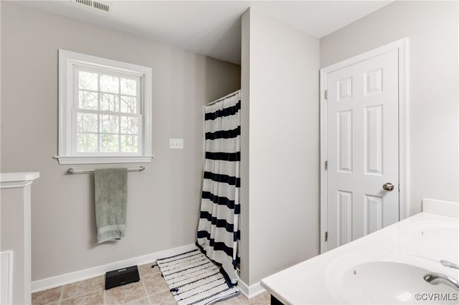 Bathroom with baseboards, curtained shower, double vanity, and tile patterned flooring | Image 17
