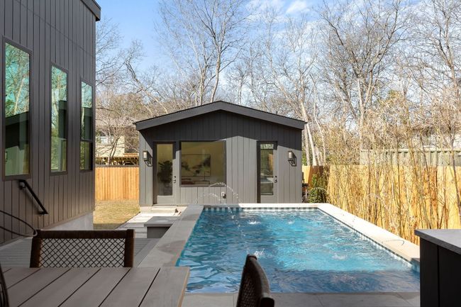 View of swimming pool featuring an outdoor structure, a storage structure, a fenced backyard, and a fenced in pool | Image 32