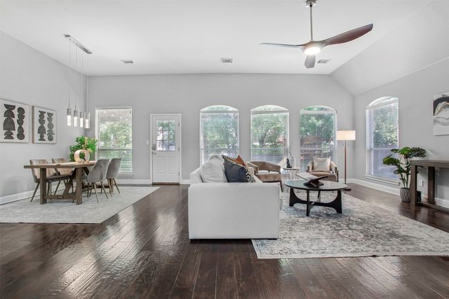 Living room featuring healthy amount of natural light, hardwood / wood-style flooring, ceiling fan, vaulted ceiling, and baseboards | Image 17