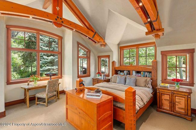 So handsome, with its vaulted ceilings, trusses, carpeted floors, windows on three sides. Disappearing TV in cabinet at end of bed. | Image 27