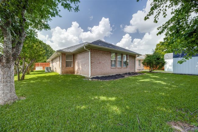 Back of house featuring brick siding, a storage shed, and roof with shingles | Image 36