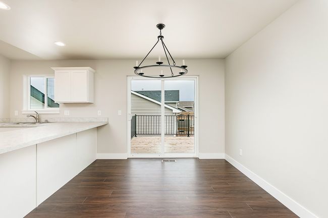 Unfurnished dining area featuring baseboards, an inviting chandelier, recessed lighting, a sink, and dark wood-type flooring | Image 8