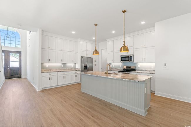 Kitchen featuring appliances with stainless steel finishes, light wood-style flooring, white cabinets, an island with sink, and recessed lighting | Image 7