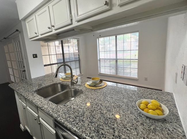 Kitchen featuring white cabinets, light stone counters, and a sink | Image 6