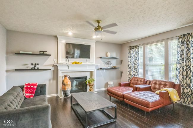 living area featuring ceiling fan, hardwood / wood-style flooring, a tile fireplace, and a textured ceiling | Image 5