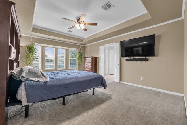 Carpeted bedroom with a raised ceiling, ornamental molding, baseboards, and ceiling fan | Image 22