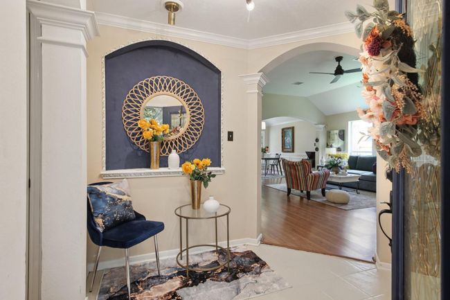 This welcoming entryway opens into a spacious living area with wood flooring, an archway, and a warm and inviting atmosphere. | Image 4