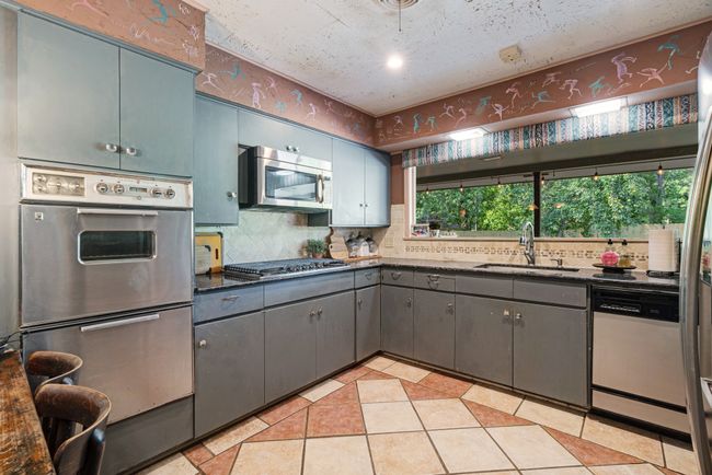 Kitchen featuring appliances with stainless steel finishes, tasteful backsplash, light tile patterned flooring, gray cabinets, and dark stone countertops | Image 8
