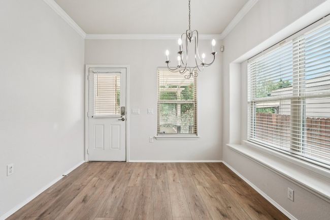 Unfurnished dining area featuring a chandelier, ornamental molding, light wood finished floors, and baseboards | Image 17