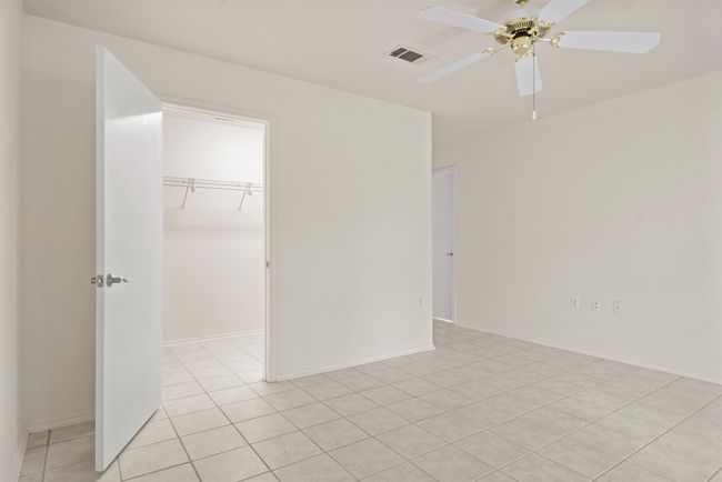 Unfurnished bedroom with light tile patterned floors, a closet, a walk in closet, and a ceiling fan | Image 14
