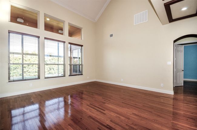 Unfurnished room with ornamental molding, plenty of natural light, arched walkways, wood finished floors, and baseboards | Image 7