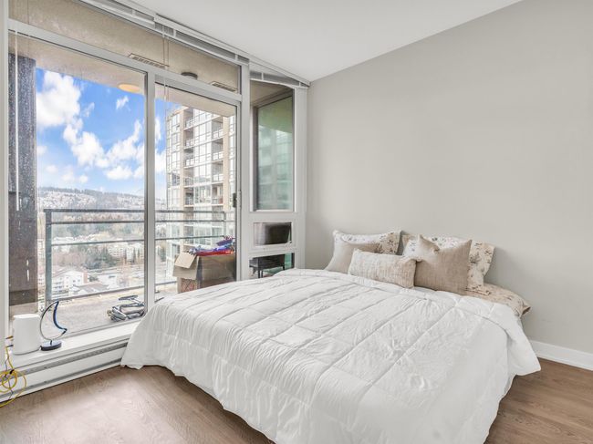Bedroom with a baseboard radiator, expansive windows, wood finished floors, and baseboards | Image 12
