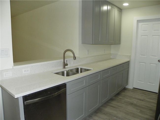 Kitchen with dishwashing machine, gray cabinetry, wood finished floors, recessed lighting, and light stone counters | Image 6