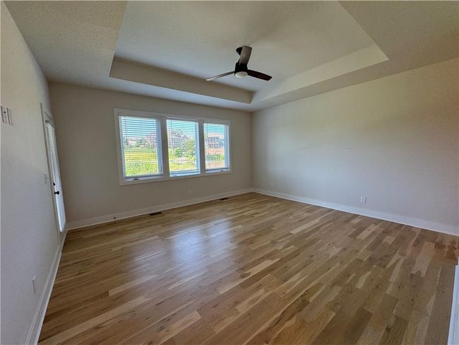 Unfurnished room featuring a raised ceiling, light wood finished floors, and a ceiling fan | Image 26