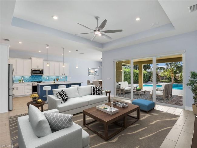 Living room featuring a raised ceiling, light hardwood / wood-style flooring, ceiling fan, and sink | Image 10