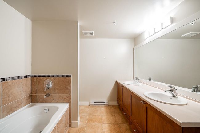 Full bathroom with baseboard heating, visible vents, a bath, and a sink | Image 13