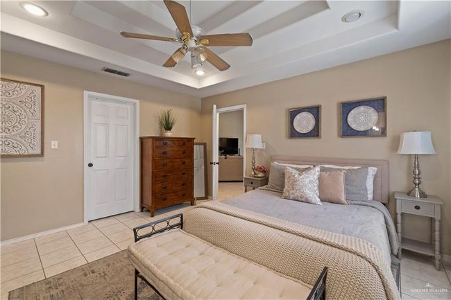 Bedroom with a tray ceiling, light tile patterned floors, recessed lighting, baseboards, and a ceiling fan | Image 22