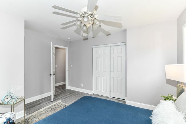 bedroom with wood finished floors, baseboards, a closet, and a ceiling fan | Image 15