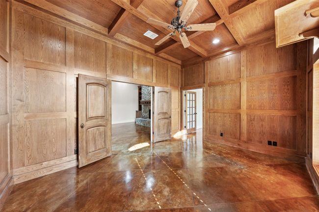 Empty room with wood ceiling with exposed beams, wood walls, coffered ceiling, ceiling fan, and french doors | Image 16
