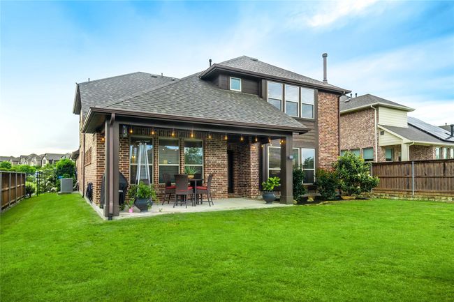 Back of house featuring a shingled roof, brick siding, central air condition unit, and a patio area | Image 31