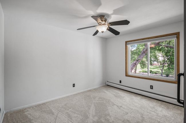 The second bedroom also boasts new plush carpet, neutral tones, tons of natural light, and a ceiling fan. | Image 20
