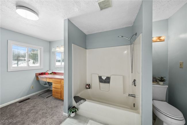 Full bathroom featuring shower / tub combination, vanity, a textured ceiling, and toilet | Image 16