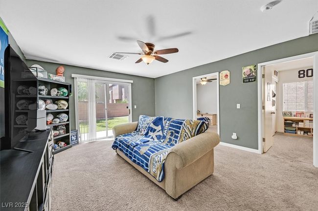 Carpeted living area featuring a ceiling fan and baseboards | Image 19
