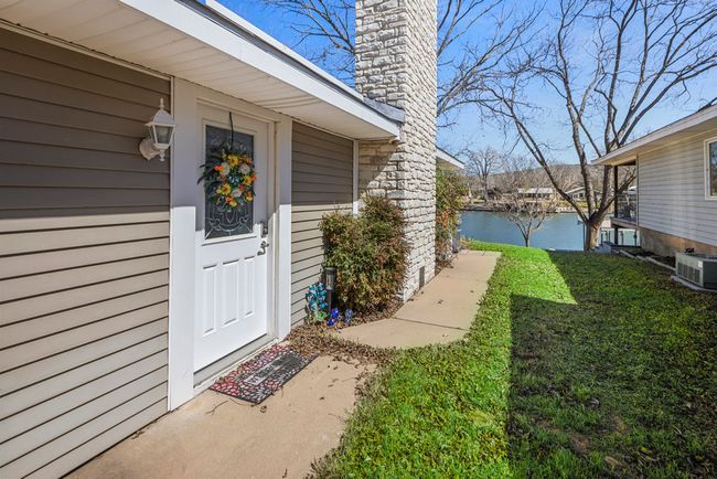 View of exterior entry featuring central air condition unit, a water view, a yard, and a chimney | Image 29