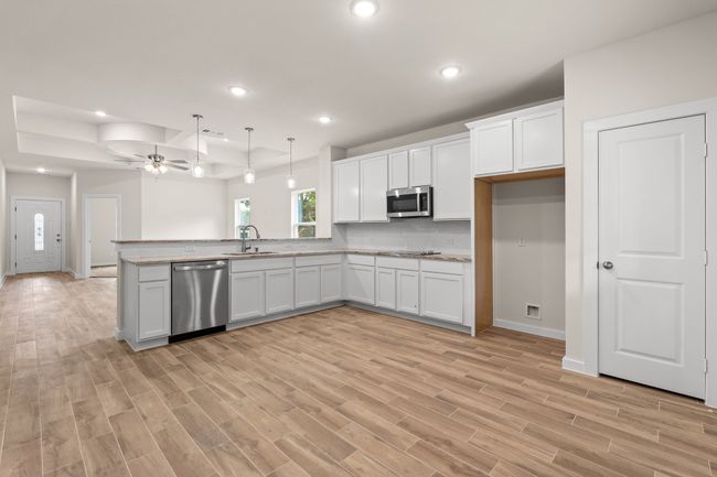 Kitchen featuring stainless steel appliances, a sink, ceiling fan, white cabinets, and light wood-style flooring | Image 13