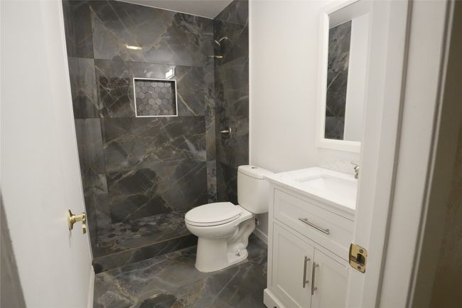 Bathroom featuring a tile shower, vanity, toilet, and marble finish floors | Image 14