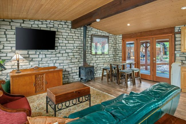 Living room featuring wood finished floors, french doors, wooden ceiling, a wood stove, and brick wall | Image 9