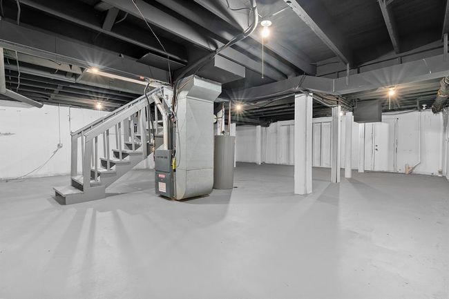 Unfinished basement featuring water heater, heating unit, and stairs | Image 23