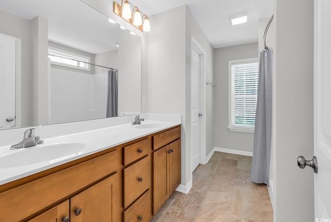 Full bath featuring plenty of natural light, double vanity, a shower with shower curtain, and baseboards | Image 23