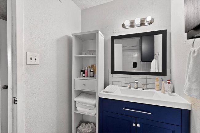 Bathroom with decorative backsplash, vanity, and a textured wall | Image 15