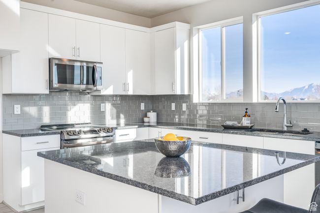 Kitchen with appliances with stainless steel finishes, a sink, healthy amount of natural light, and dark stone counters | Image 9
