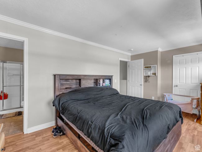 Bedroom with ornamental molding, light wood-style flooring, and baseboards | Image 24