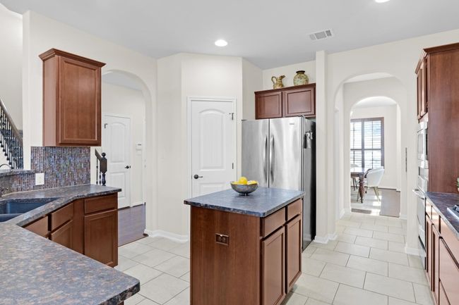 Kitchen featuring dark countertops, backsplash, center island and arched walkways | Image 11