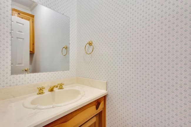 Half bath down stairs with wallpapered walls, vanity, and crown molding | Image 12