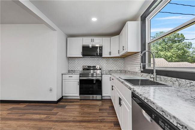 Kitchen featuring appliances with stainless steel finishes, a sink, decorative backsplash, dark wood-style floors, and recessed lighting | Image 18