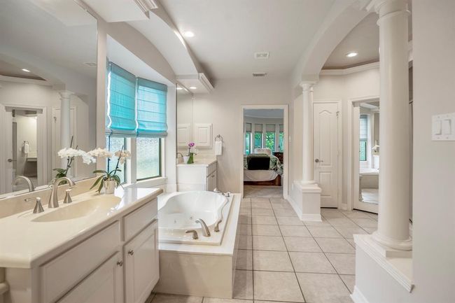 Dual sinks on opposite ends of the tub, tiled flooring, and as well as a separate shower with dual shower heads and twin closets. | Image 23
