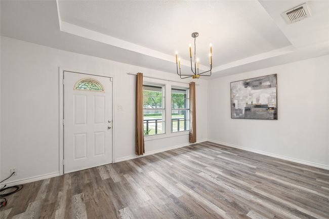 Entryway featuring a raised ceiling, a chandelier, wood finished floors, and baseboards | Image 5