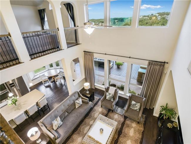 Living area featuring wood finished floors, a towering ceiling, and a ceiling fan | Image 9