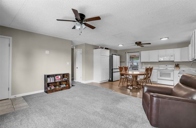 Carpeted living room with ceiling fan, a textured ceiling, baseboards, and a sink | Image 7