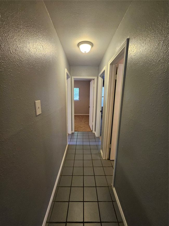Corridor featuring tile patterned flooring, baseboards, and a textured wall | Image 18